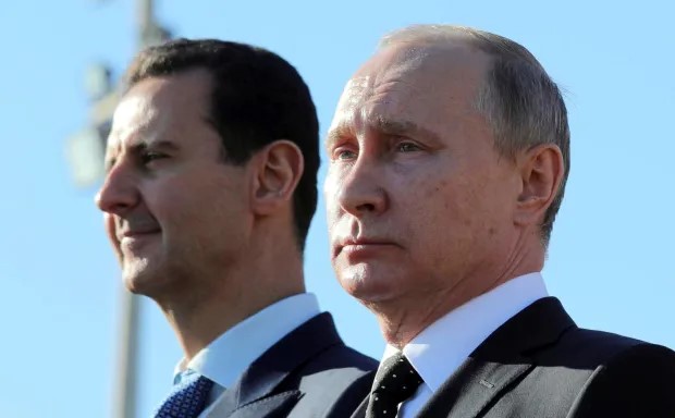 Bashar al-Assad and Vladimir Putin standing side-by-side.