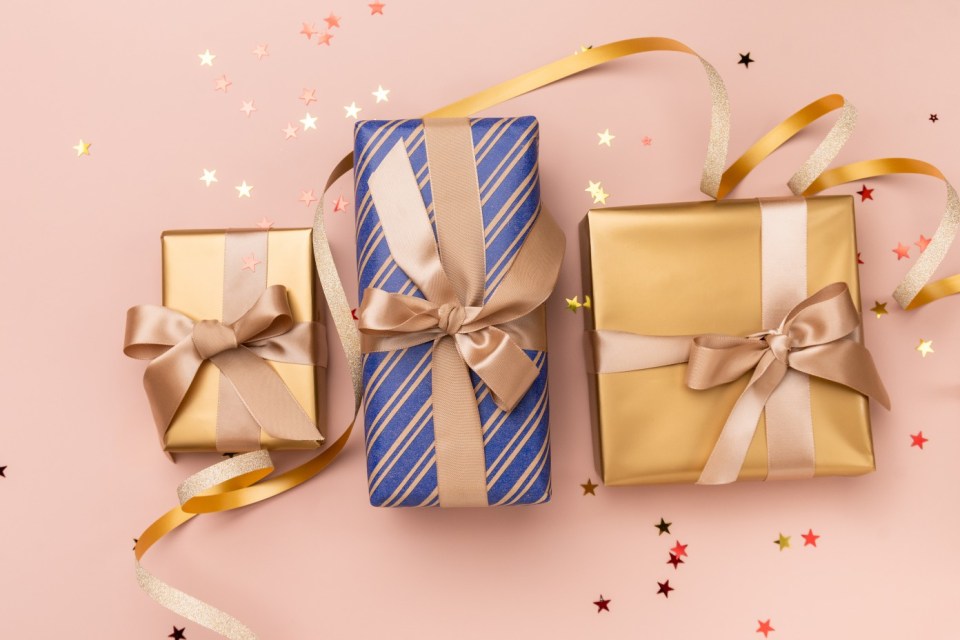 Three gifts wrapped in gold and blue paper with gold ribbons and confetti.