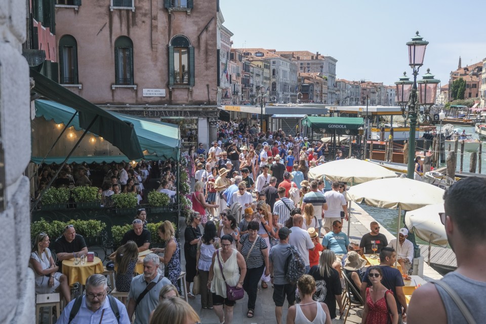 Tourists crowd the area near the Rialto Bridge in Venice