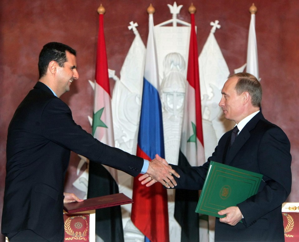 Assad (L) and Putin (R) shake hands during a meeting