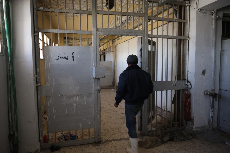 A man walks into an empty cell block in Sednaya Prison