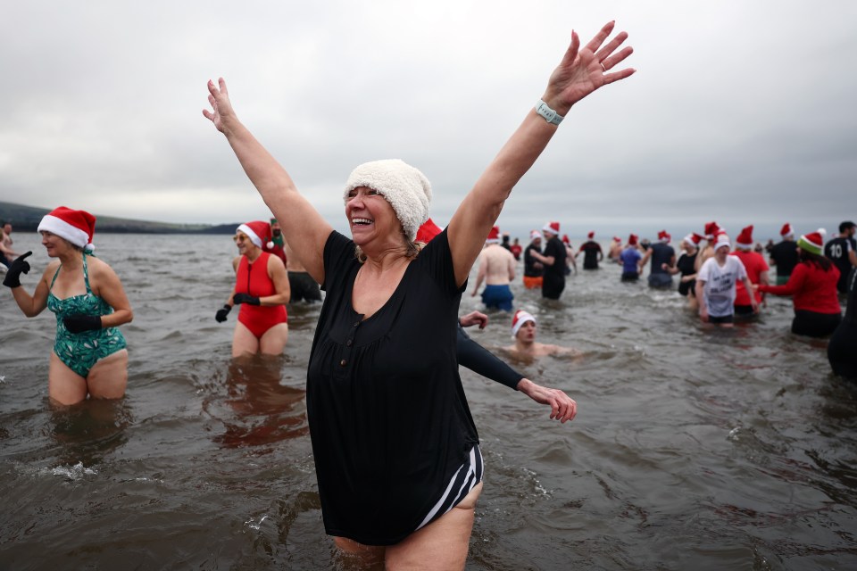 A woman joyfully participates in a charity Boxing Day swim.