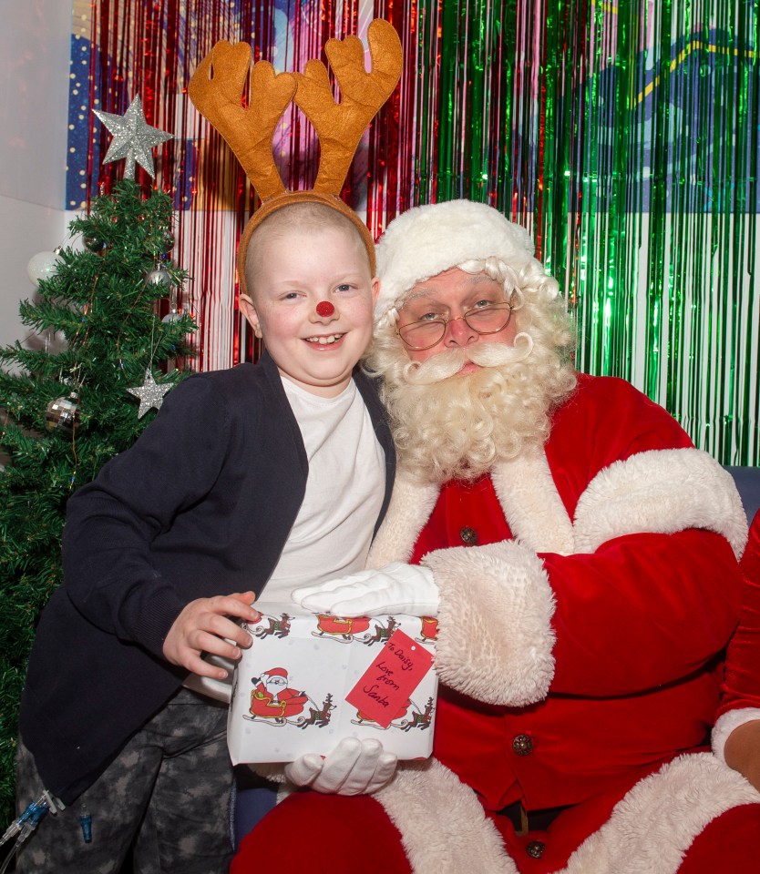 Daisy Tullett receives her present from Santa – in the paper she designed for our fundraiser in aid of sick children