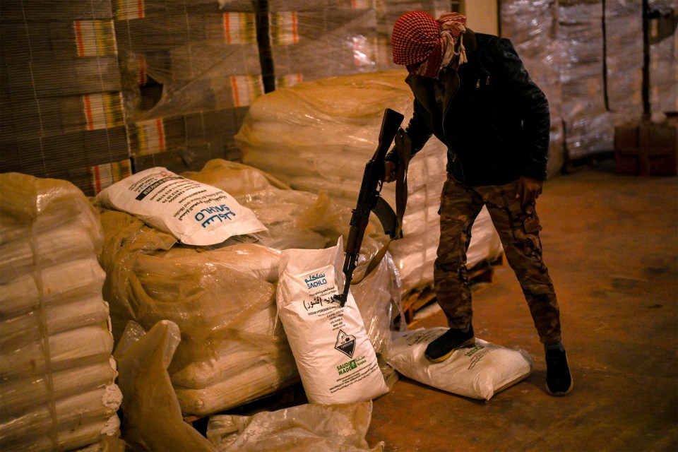 Syrian rebel fighters inspect sacks marked to contain 'Saudi-made' flakes of caustic soda at a drug manufacturing facility