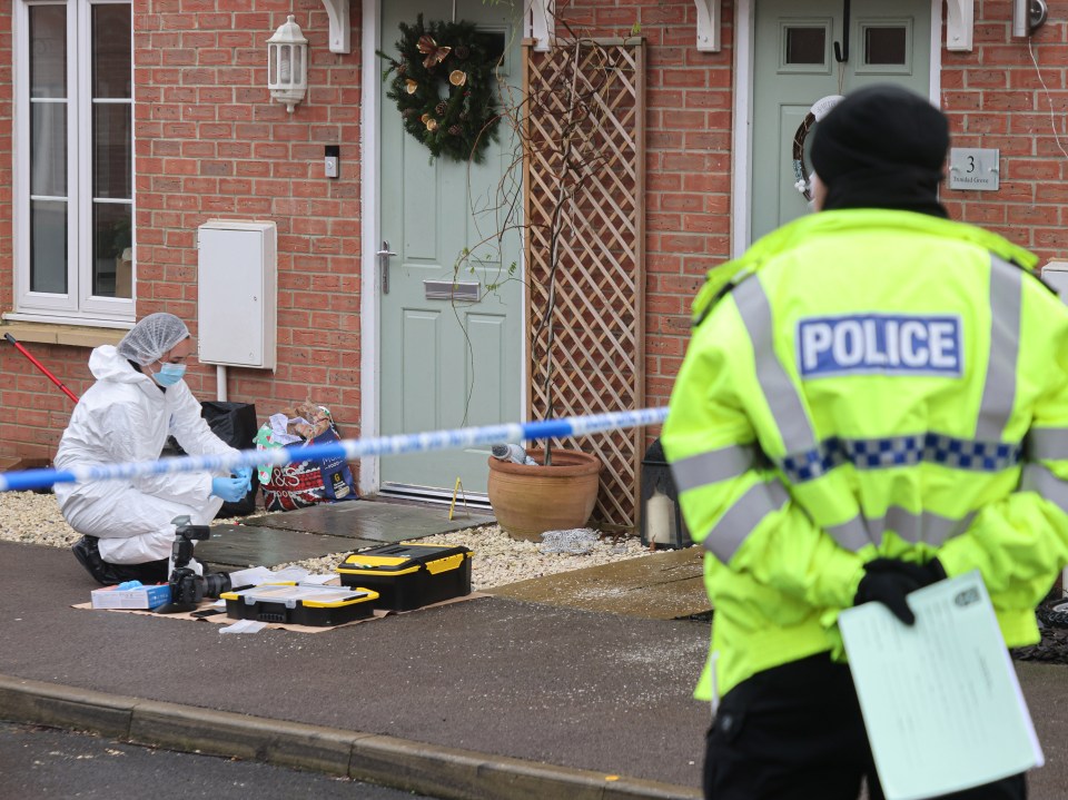 Forensic officers investigate a crime scene outside a house.