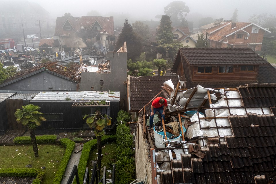 A man checks the damages on a roof caused by a plane crash