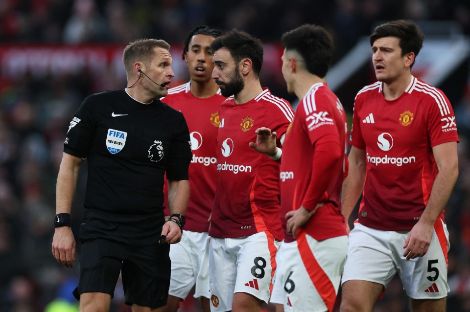 Manchester United players argue with a referee.