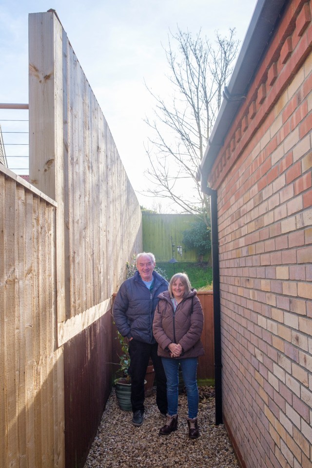 Mike Oldham and Dawn Brooke alongside a 14ft fence that has been built