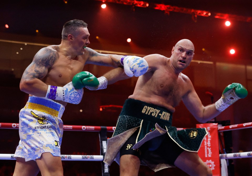 Oleksandr Usyk throwing a punch at Tyson Fury in a boxing match.