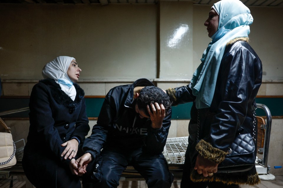 A man is comforted after searching for missing relatives at the morgue of Al-Mujtahid hospital in Damascus