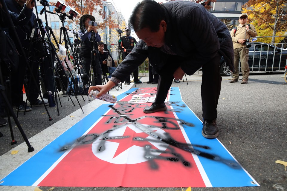 A protester spray-paints a North Korean flag during an anti-North Korea rally in Seoul.