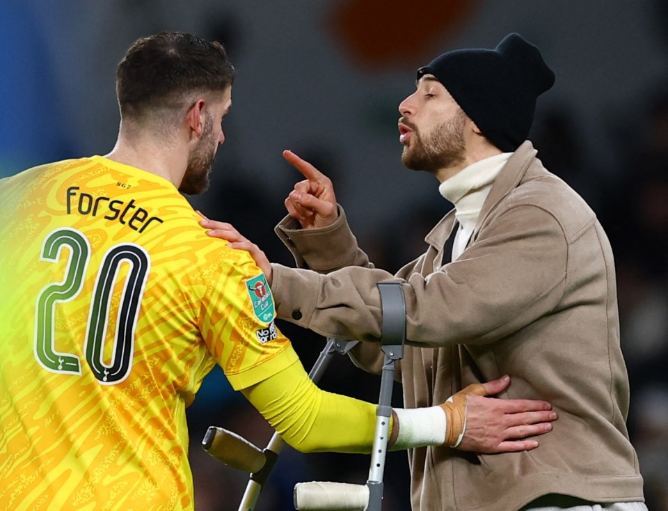 Fraser Forster of Tottenham Hotspur speaks with an injured person on crutches.