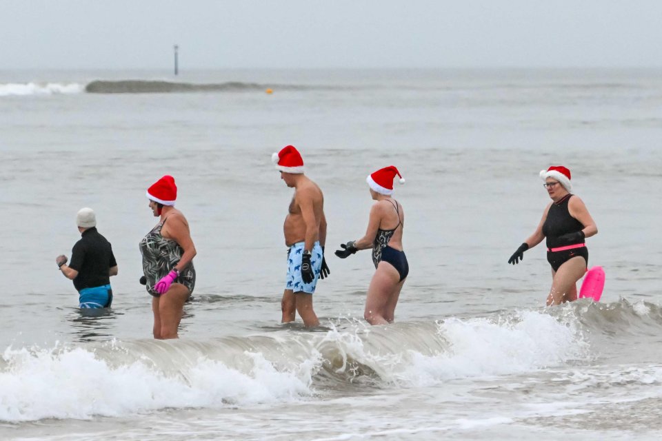 Christmas Day swimmers in Mudeford, Dorset, were watched by others who had wrapped up warm and remained on shore