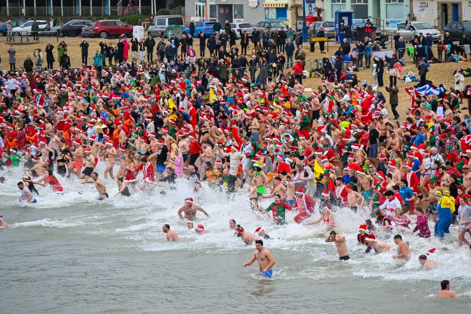 Hundreds of people in Christmas costumes participate in a charity dip in the sea.