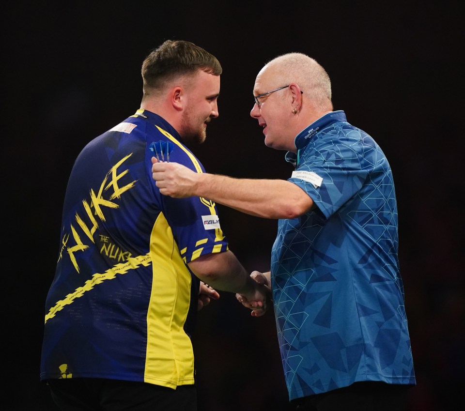 Luke Littler shakes hands with Ian White after a darts match.