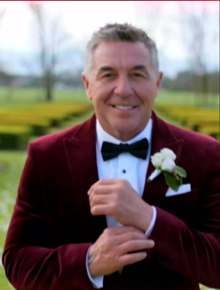 Groom in a burgundy velvet tuxedo adjusting his cufflinks.