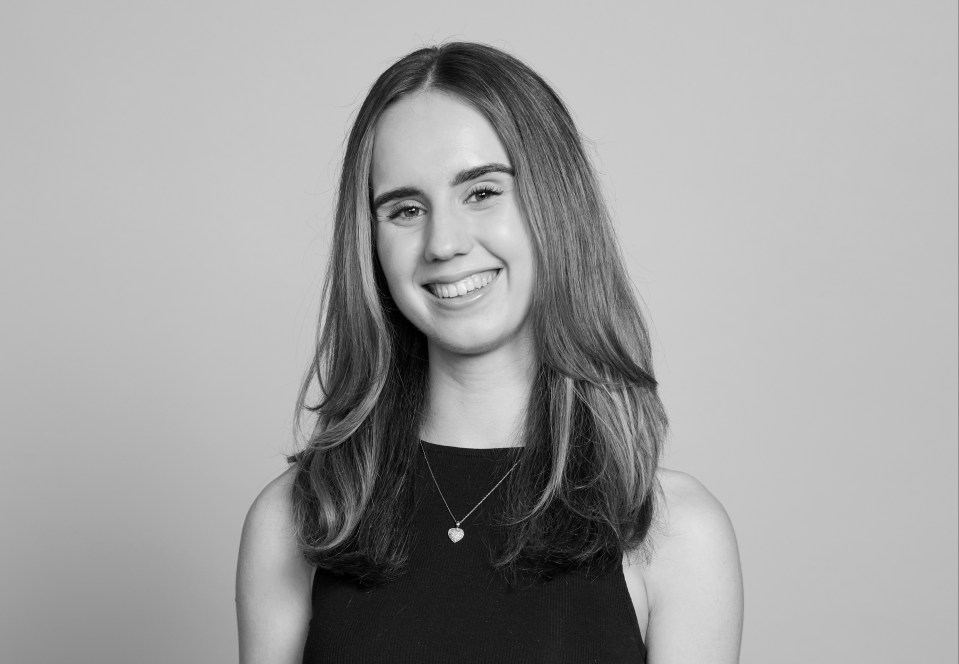 Black and white portrait of a smiling young woman wearing a black dress.