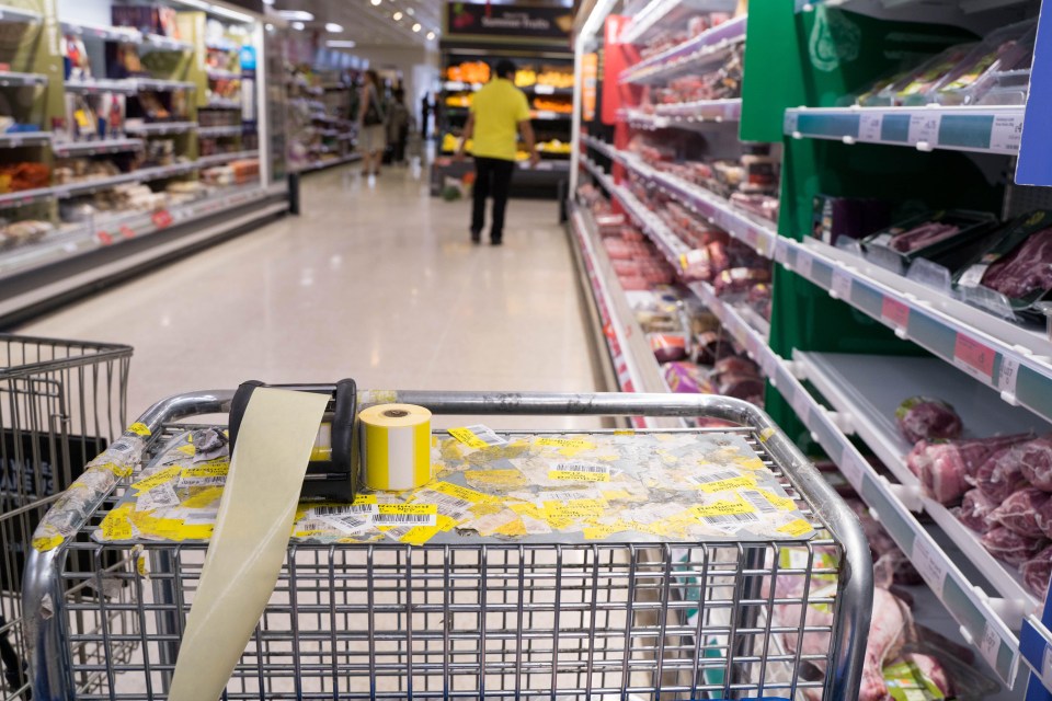 Shopping cart in supermarket with discarded yellow discount stickers.