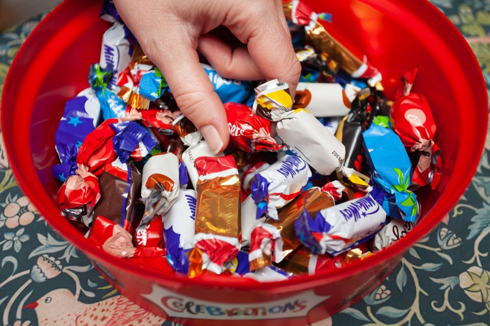 Hand reaching into a bowl of Celebrations chocolates.