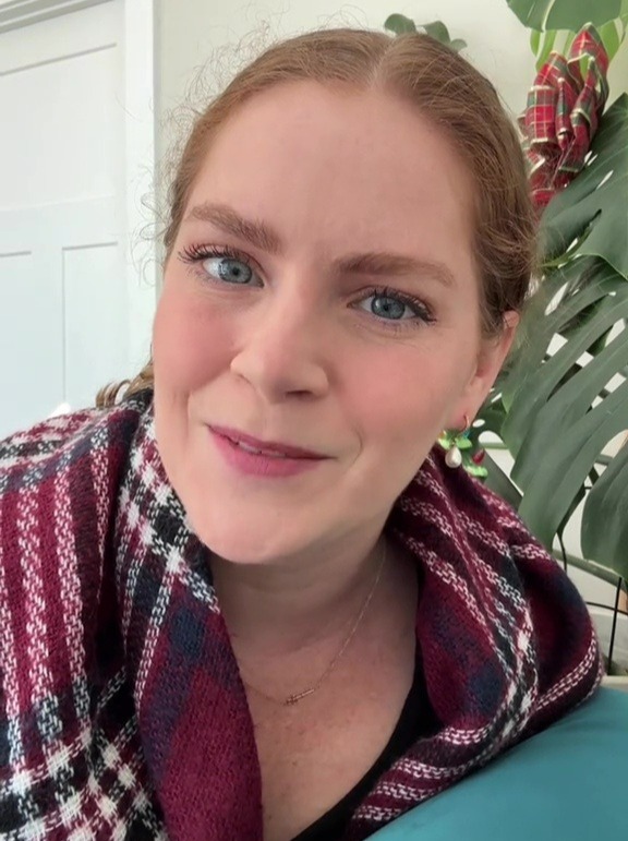 Woman in a red and black plaid scarf smiling at the camera.