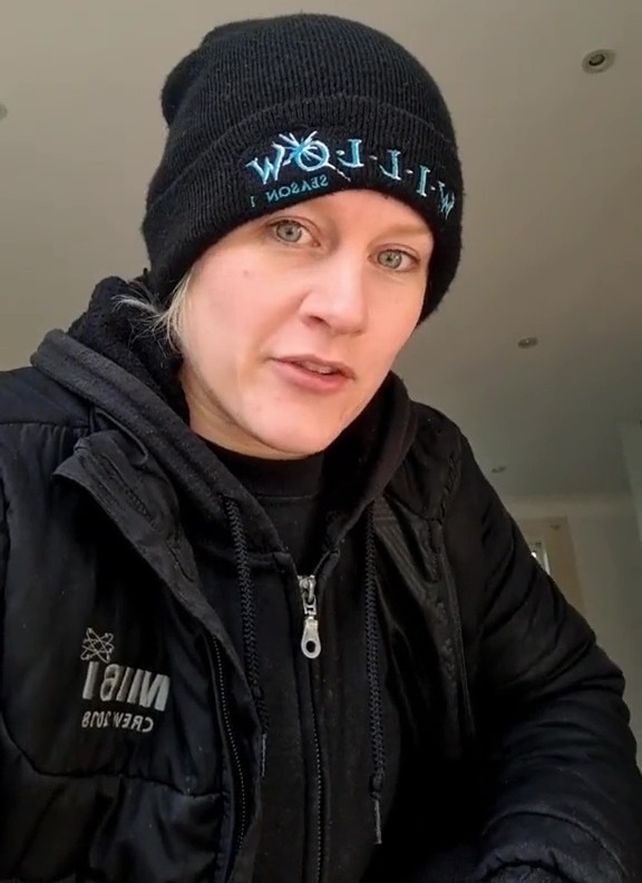 Woman in black beanie and jacket explains a damp home solution.