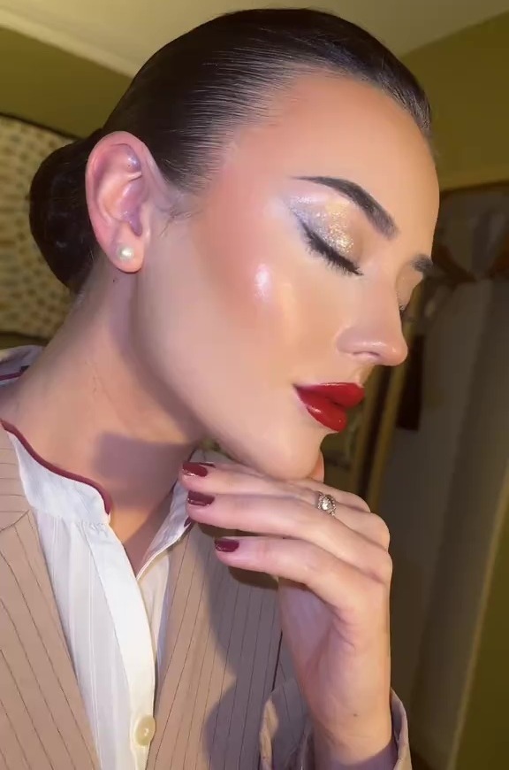 Close-up of a flight attendant with red lipstick and sparkly eye makeup.