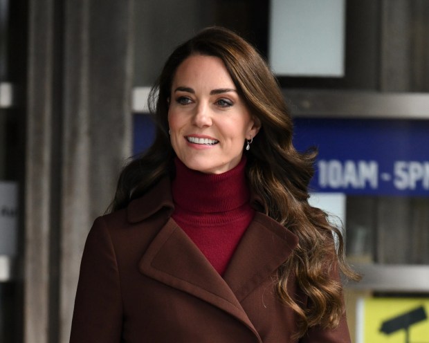 Catherine, Princess of Wales, wearing a brown coat and red turtleneck, during an official visit.