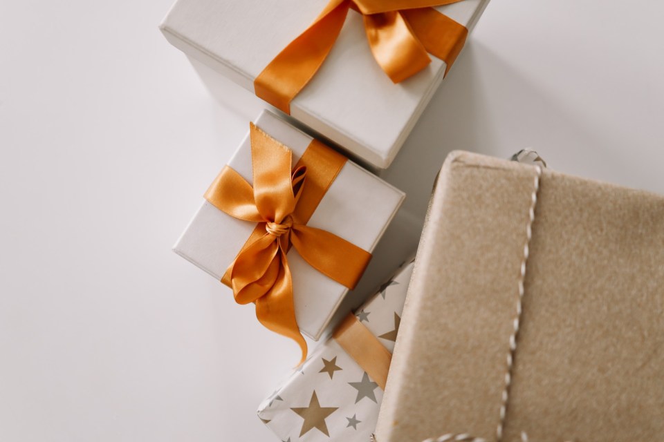 Several gifts wrapped in white and brown paper with gold ribbons.