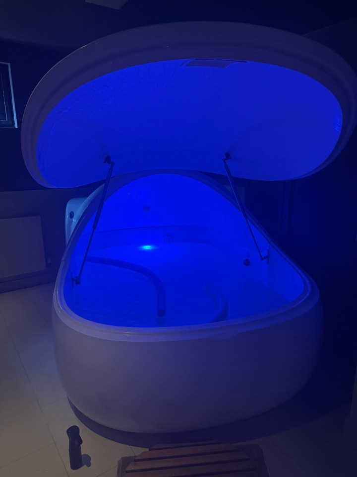 Floatation tank with lid open, illuminated in blue.