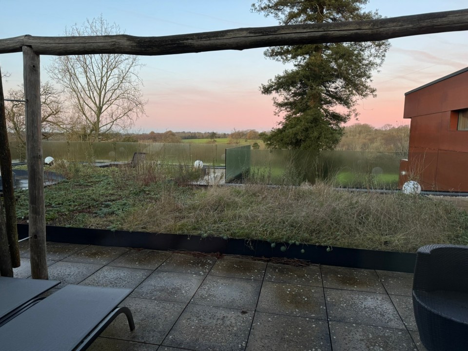 Rooftop patio with view of sunset over fields.