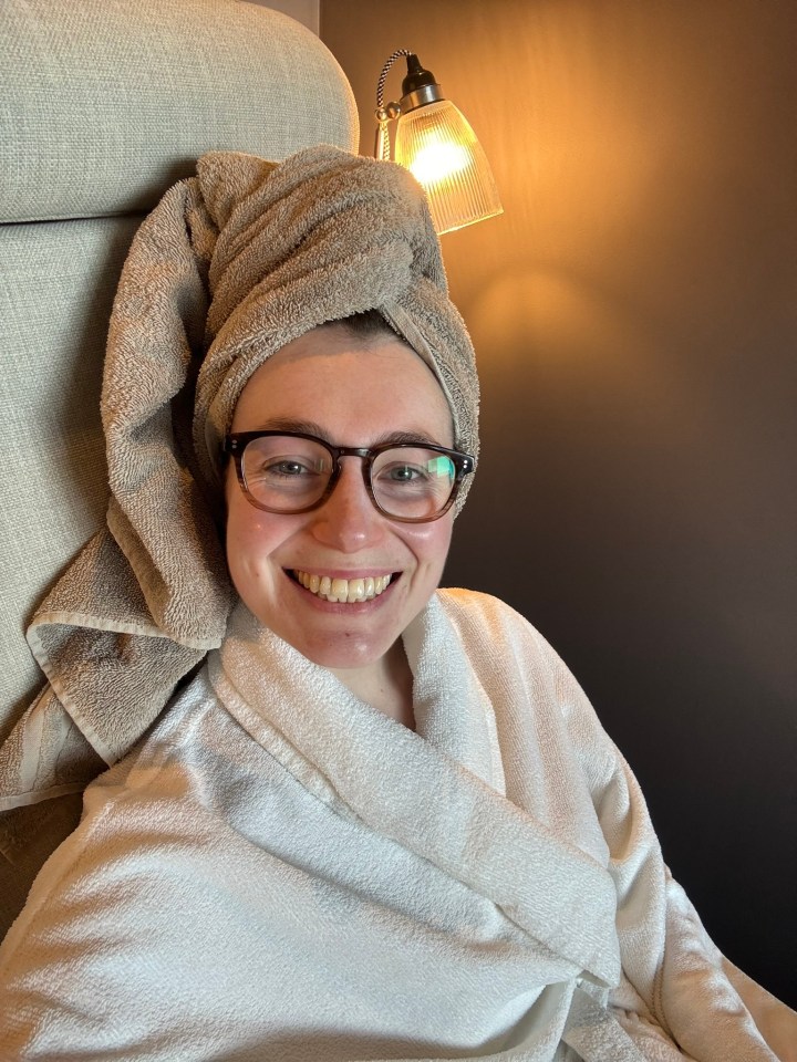 Woman in bathrobe and towel on her head smiling.