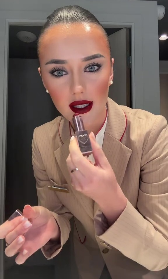 Air stewardess applying red lipstick.