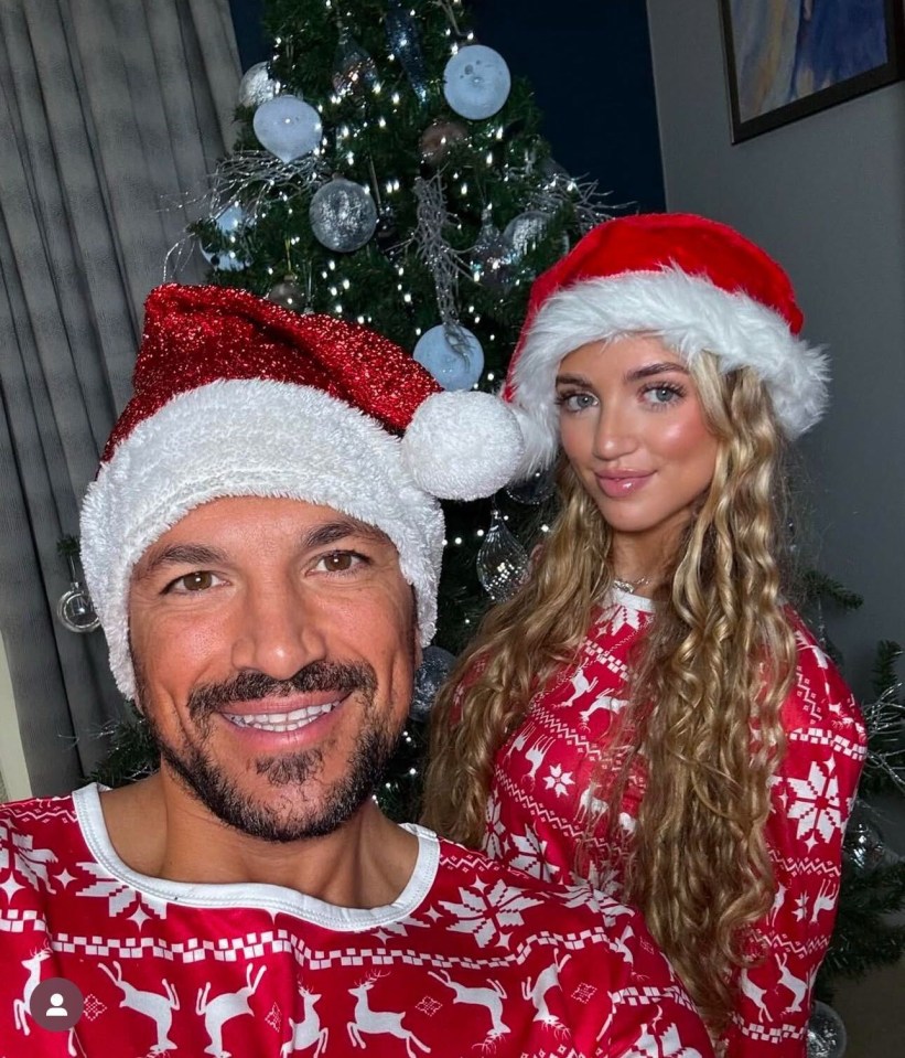 Couple in matching Christmas pajamas in front of a decorated tree.