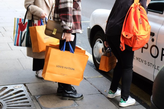 Shoppers with Louis Vuitton bags hail a cab on Oxford Street.