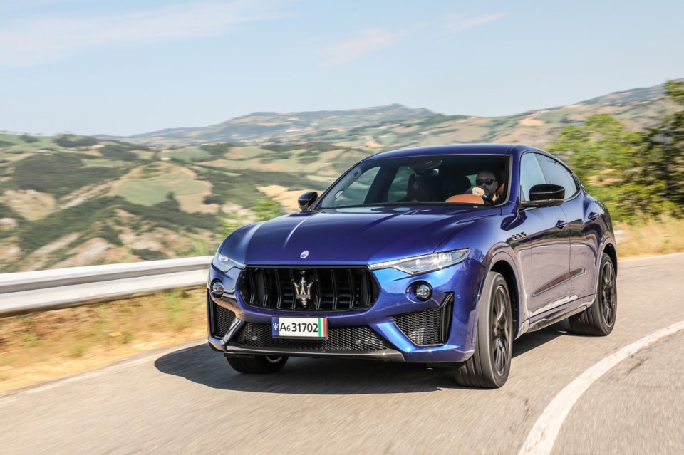 A blue Maserati Levante Trofeo driving on a winding road.