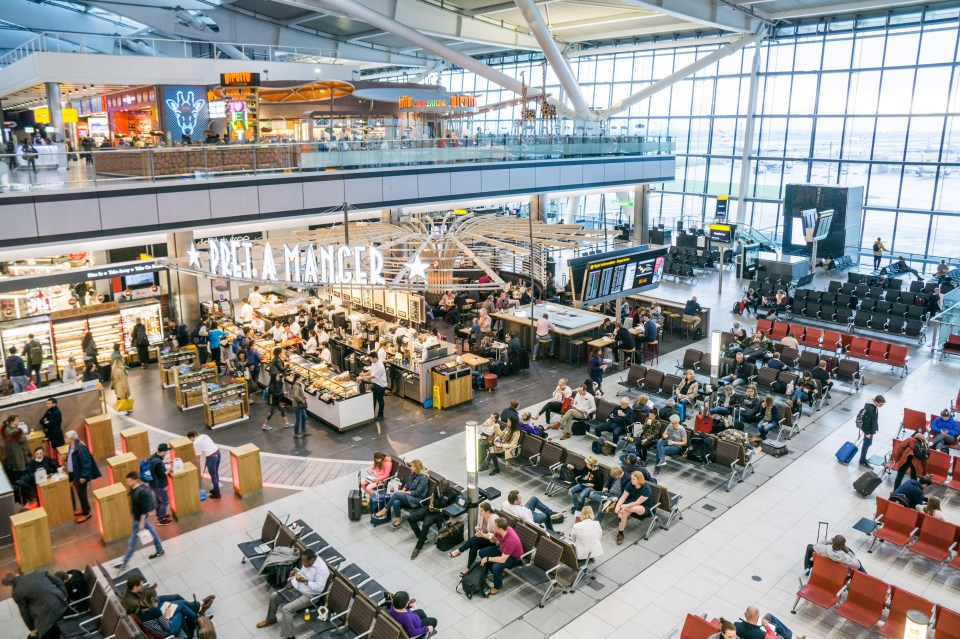 Heathrow Airport Terminal 5 retail area with passengers waiting and shops.