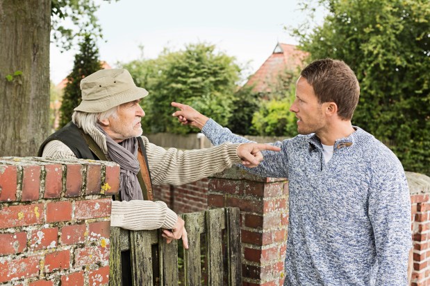 Two men arguing by a brick wall.