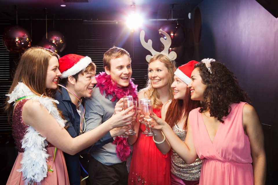 Group of young adults toasting with champagne at a Christmas party.