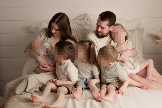 Family portrait of parents and five children on a bed.