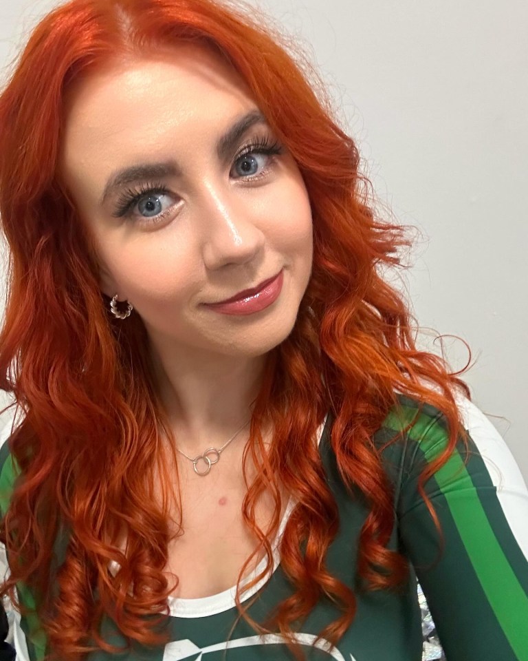 Woman with long, curly red hair wearing a green and white shirt.