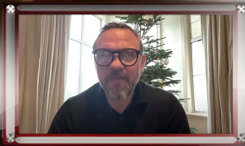 Man in glasses in video call, Christmas tree in background.