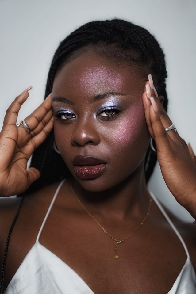 Close-up of a woman with braids, iridescent makeup, and long nails.