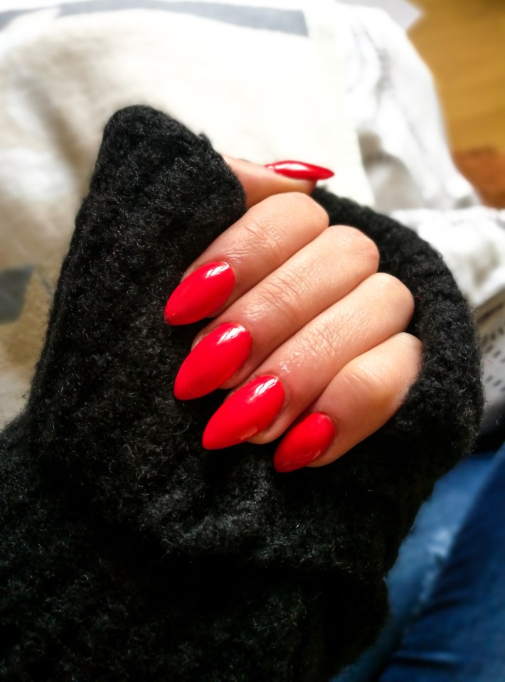 Woman's hand with long, red, pointed nails.