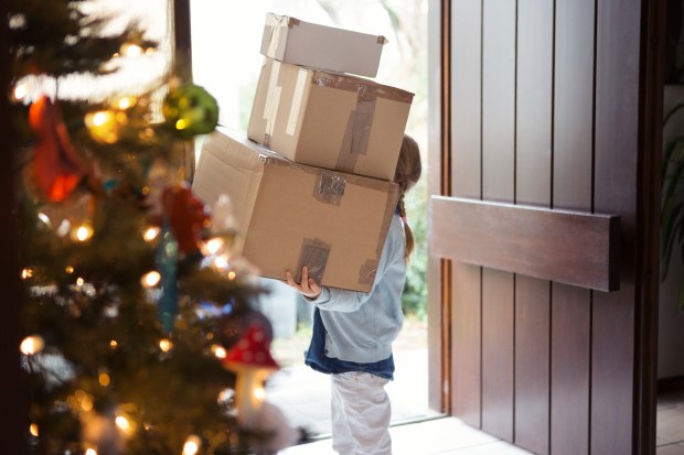 Girl carrying Christmas presents into her home.