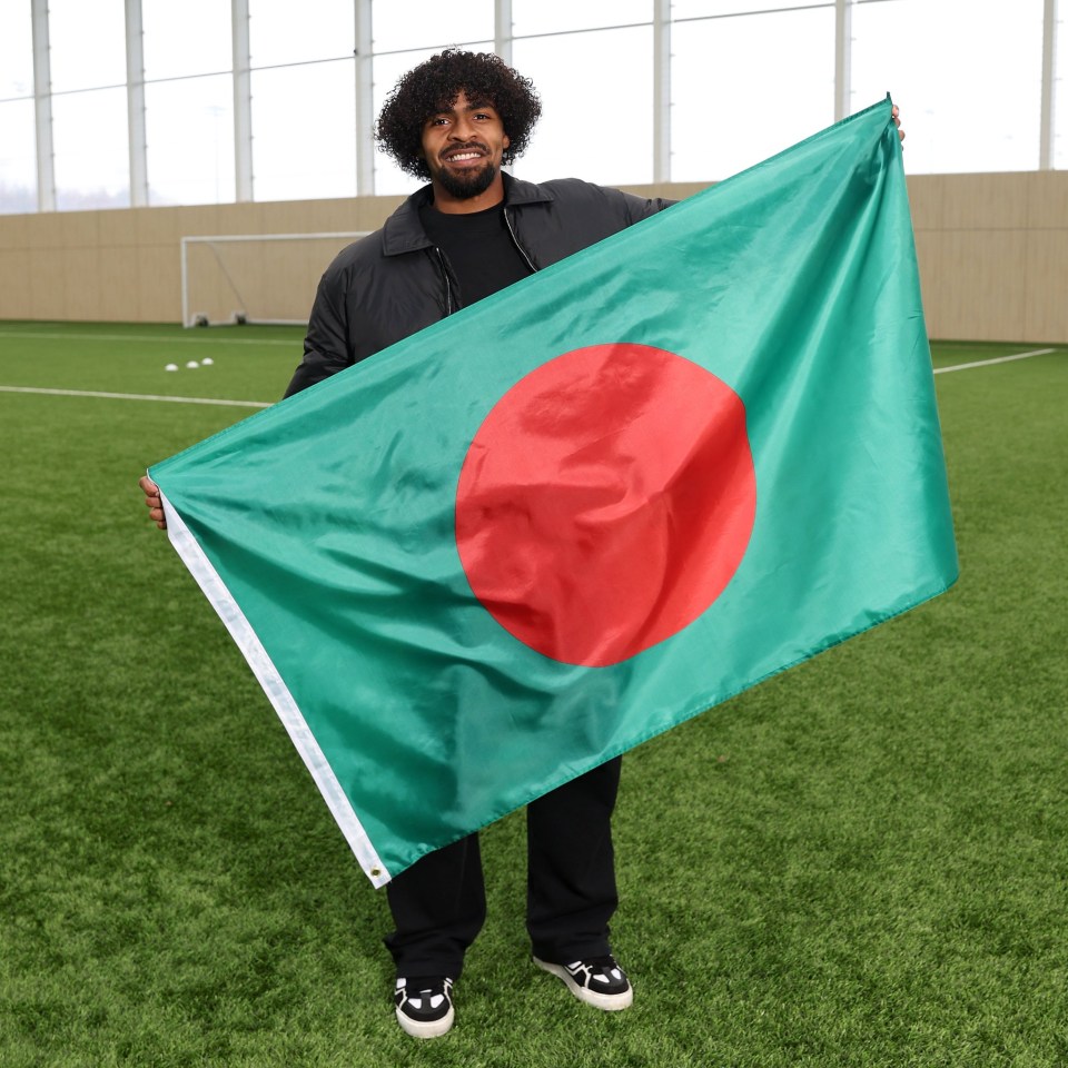 Man holding the Bangladeshi flag on a soccer field.