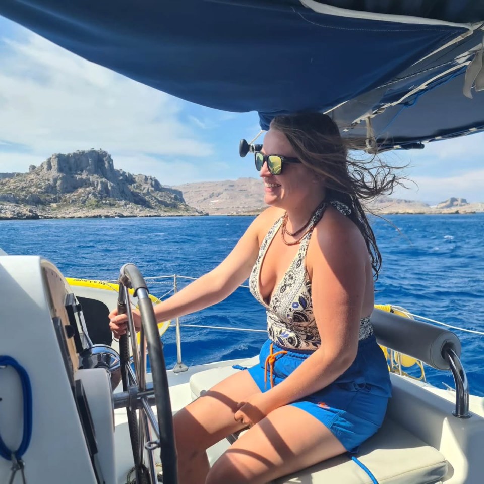 Woman steering a sailboat at sea.