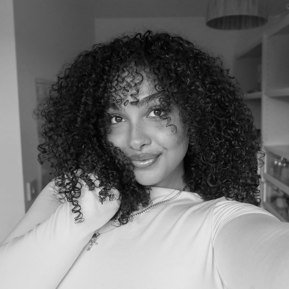 Black and white selfie of a young woman with curly hair.