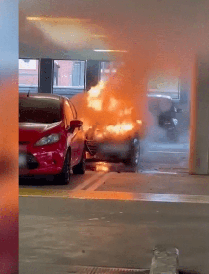 Car engulfed in flames in a parking garage.