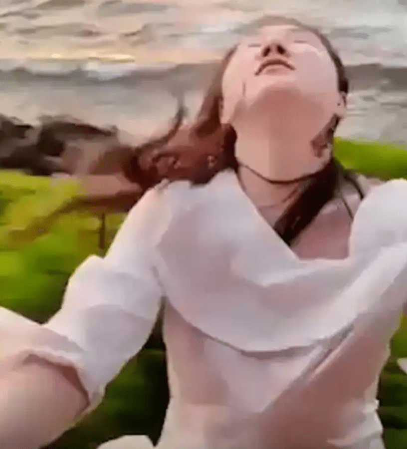 Woman in white shirt near ocean.