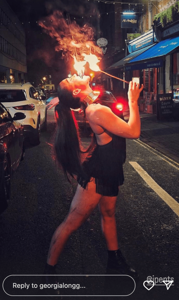 Woman fire breathing on a city street.